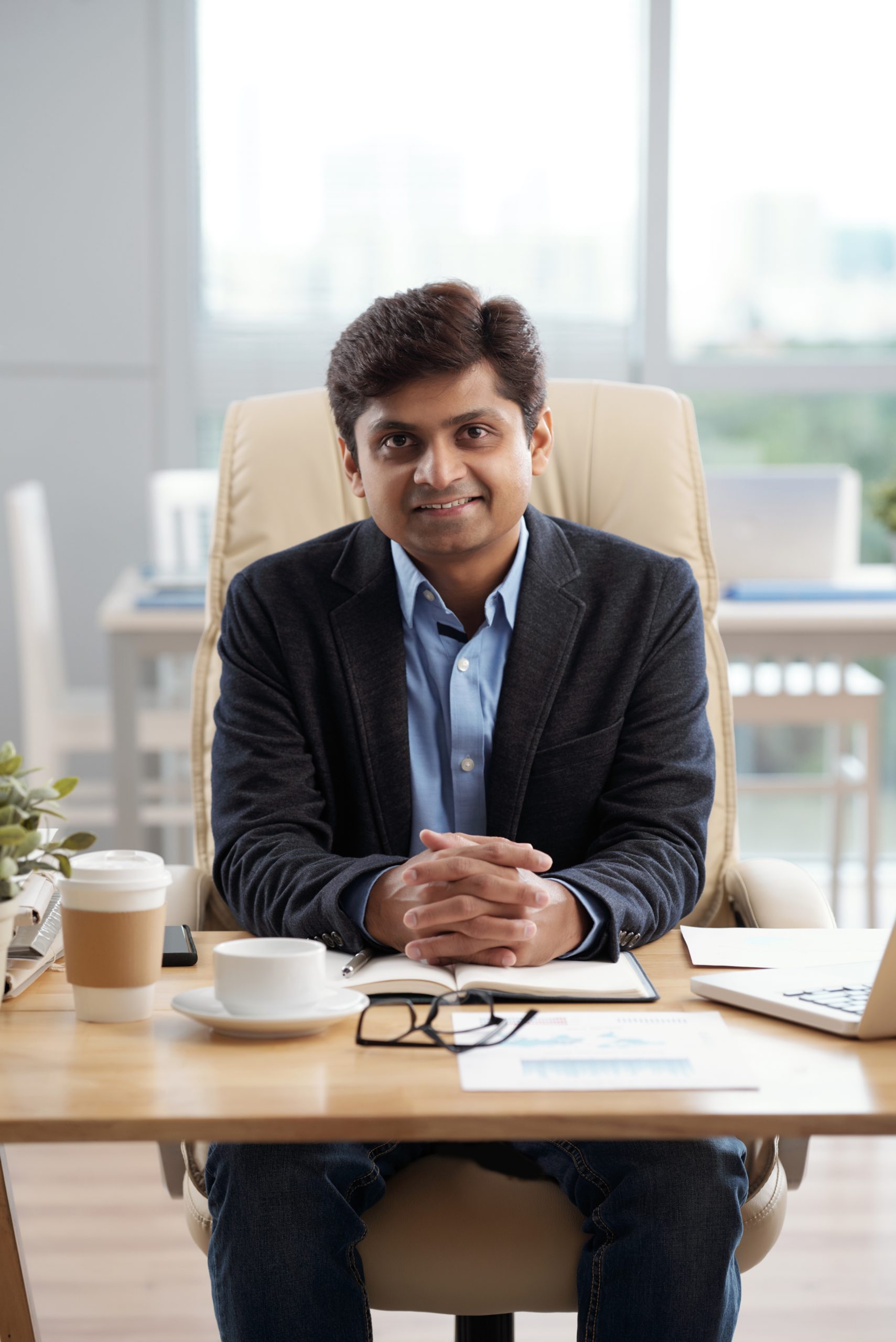 Confident smiling CEO of company sitting at his office table